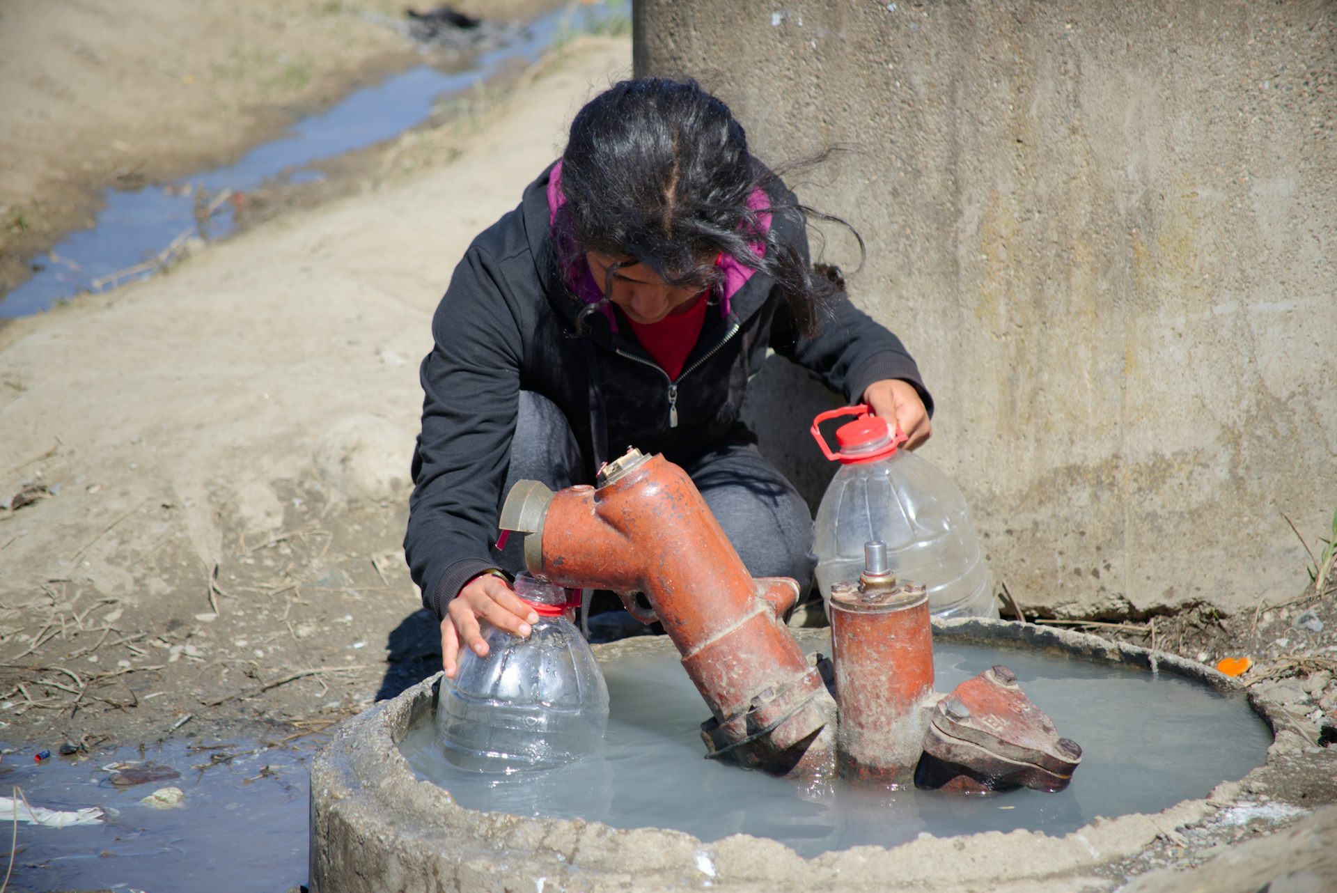 A girl filling a five litre bottle at a water station in a refugee camp