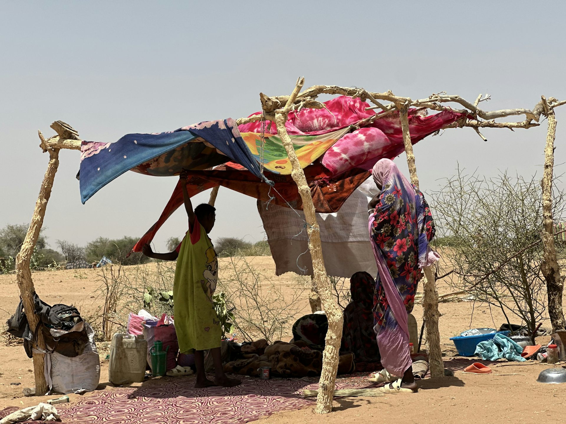 Sudanese people under a makeshift shelter in a desert region of Sudan.