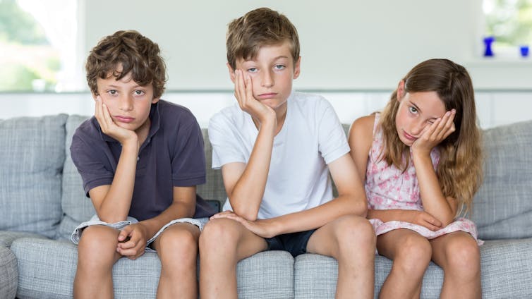 A young child lying on a couch looking bored, illustrating how downtime and unstructured time can support creativity and emotional regulation.