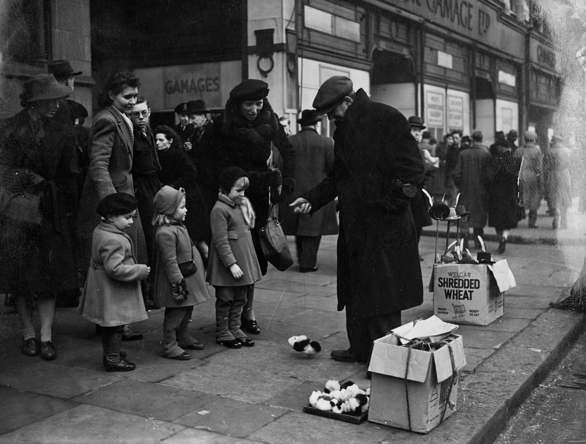 A black and white photo of a street vendor showing children mechanical toys