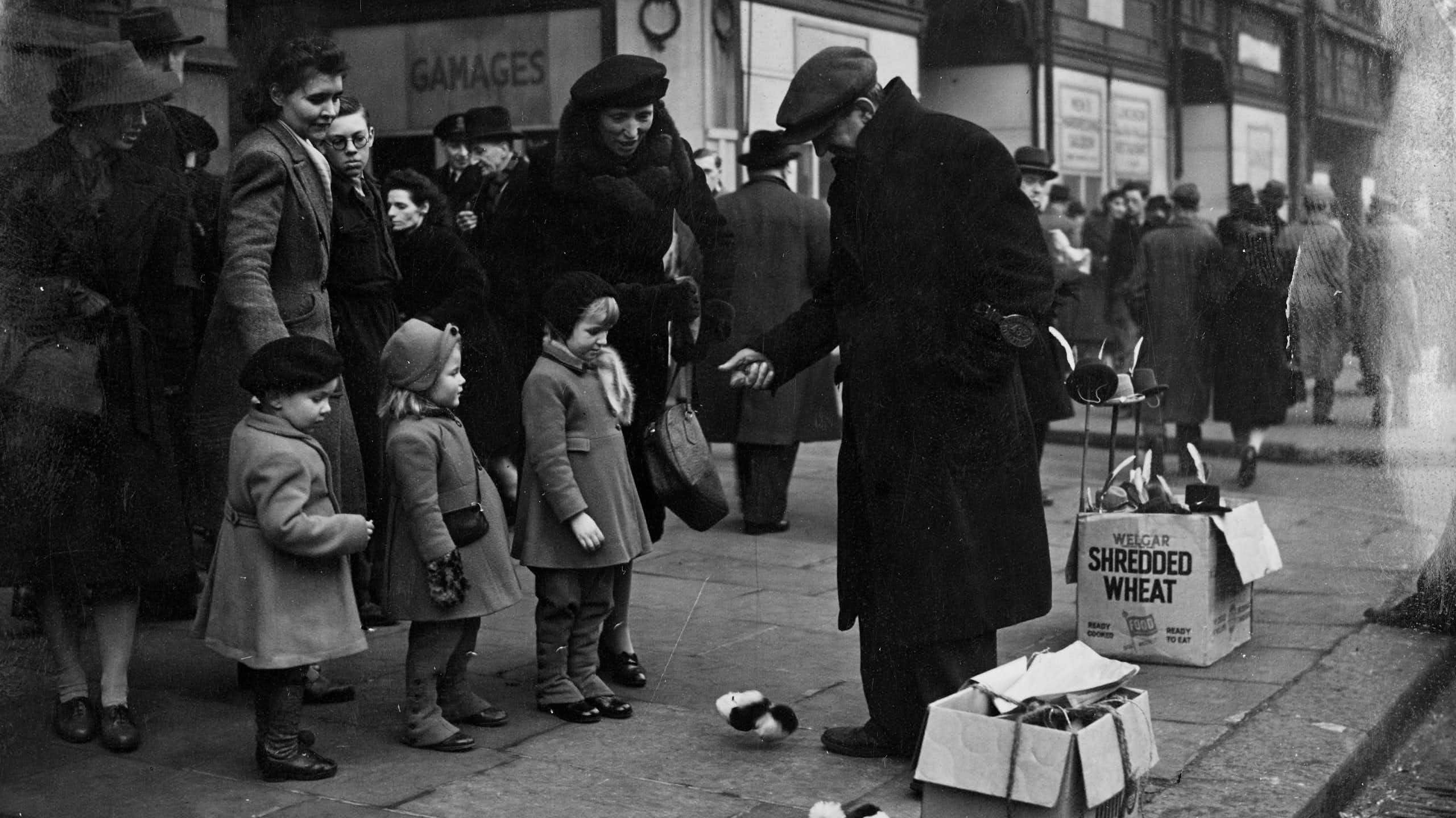 A black and white photo of a street vendor showing children mechanical toys