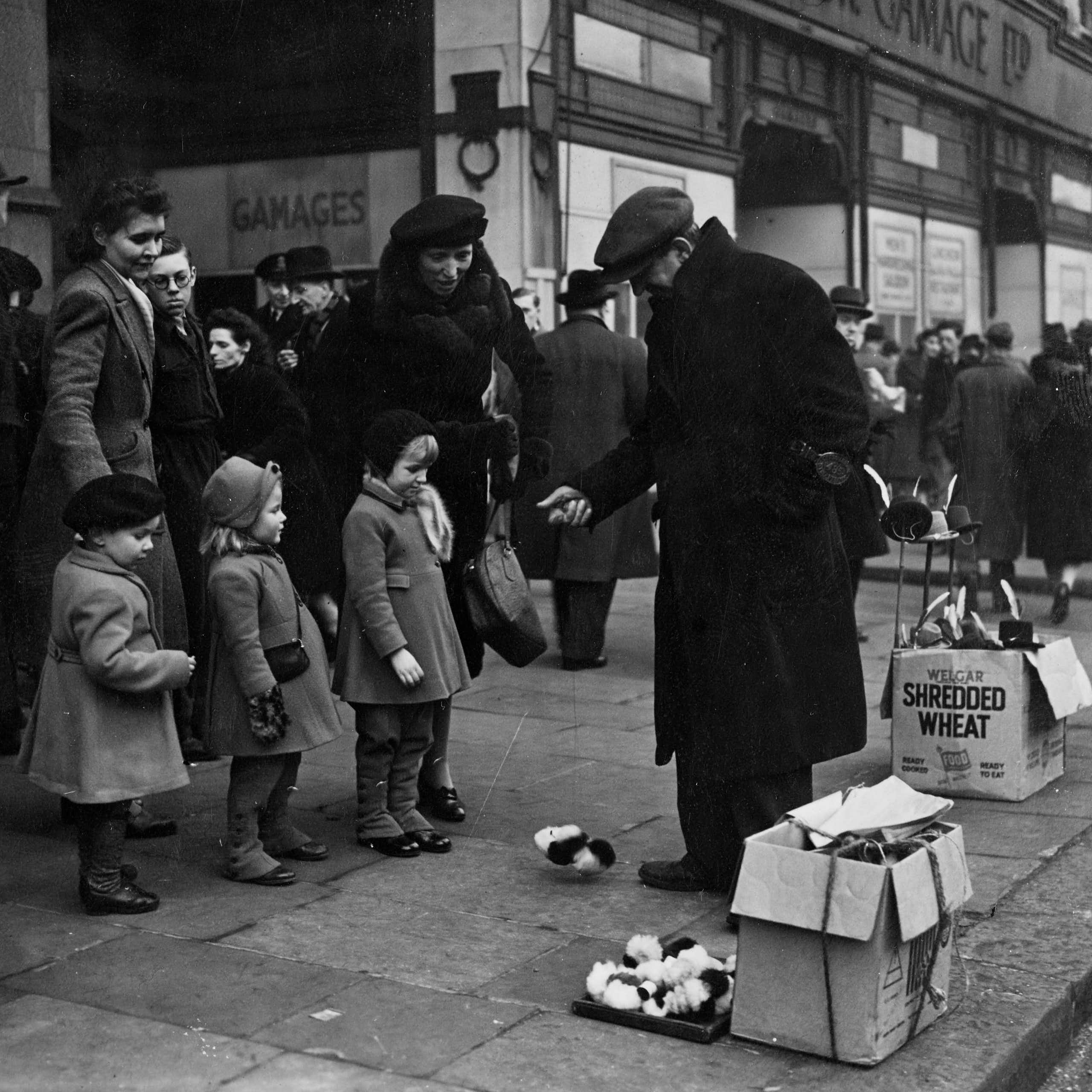 A black and white photo of a street vendor showing children mechanical toys