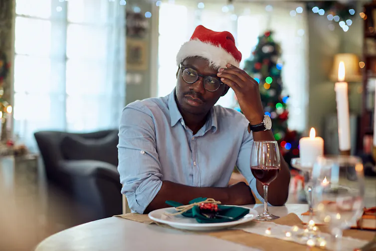 Man looks sad while sitting alone at a Christmas dinner table