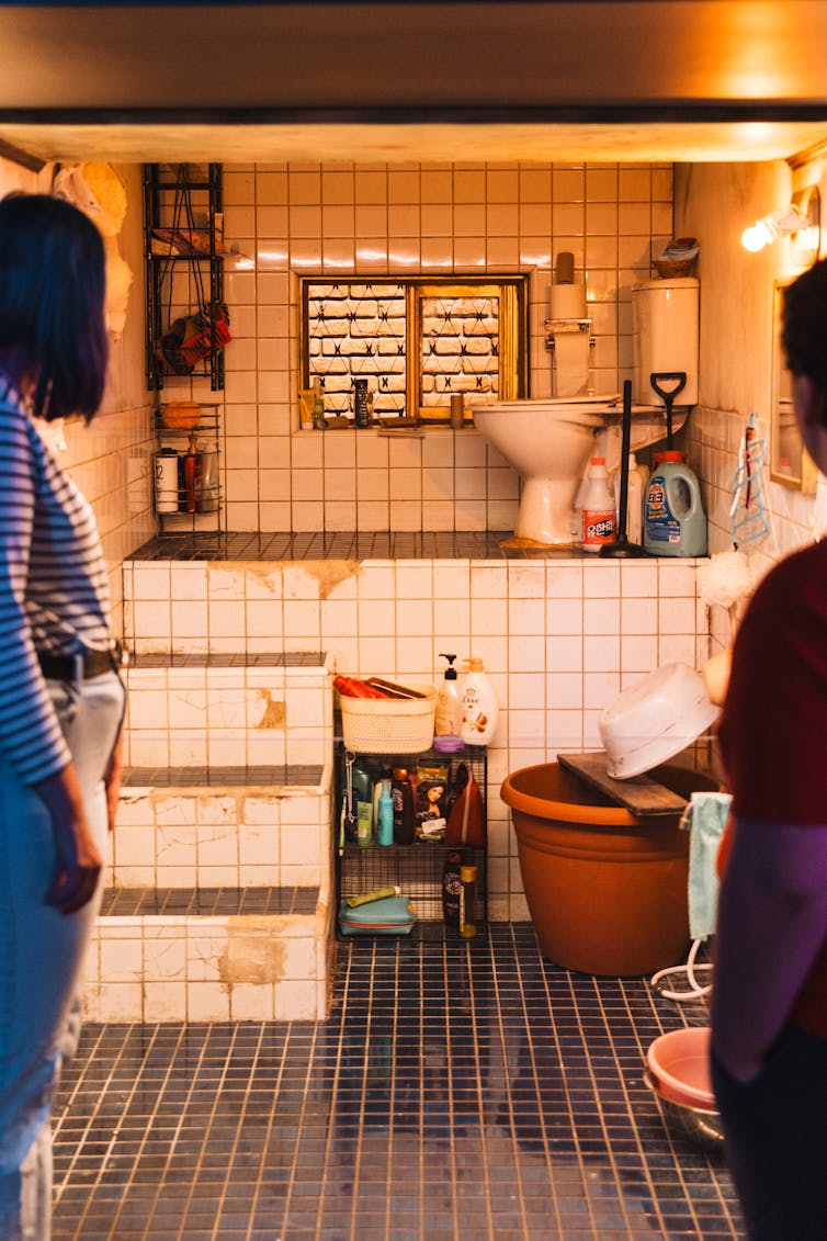 Two visitors look in on the bathroom.