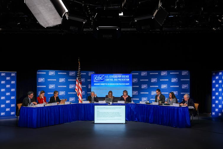 RFK Jr. needs to scrutinize the vaccine time table – however its protection report is already a long time lengthy 2 Members of the CDC Advisory Committee on Immunization Practices sitting at a long table.