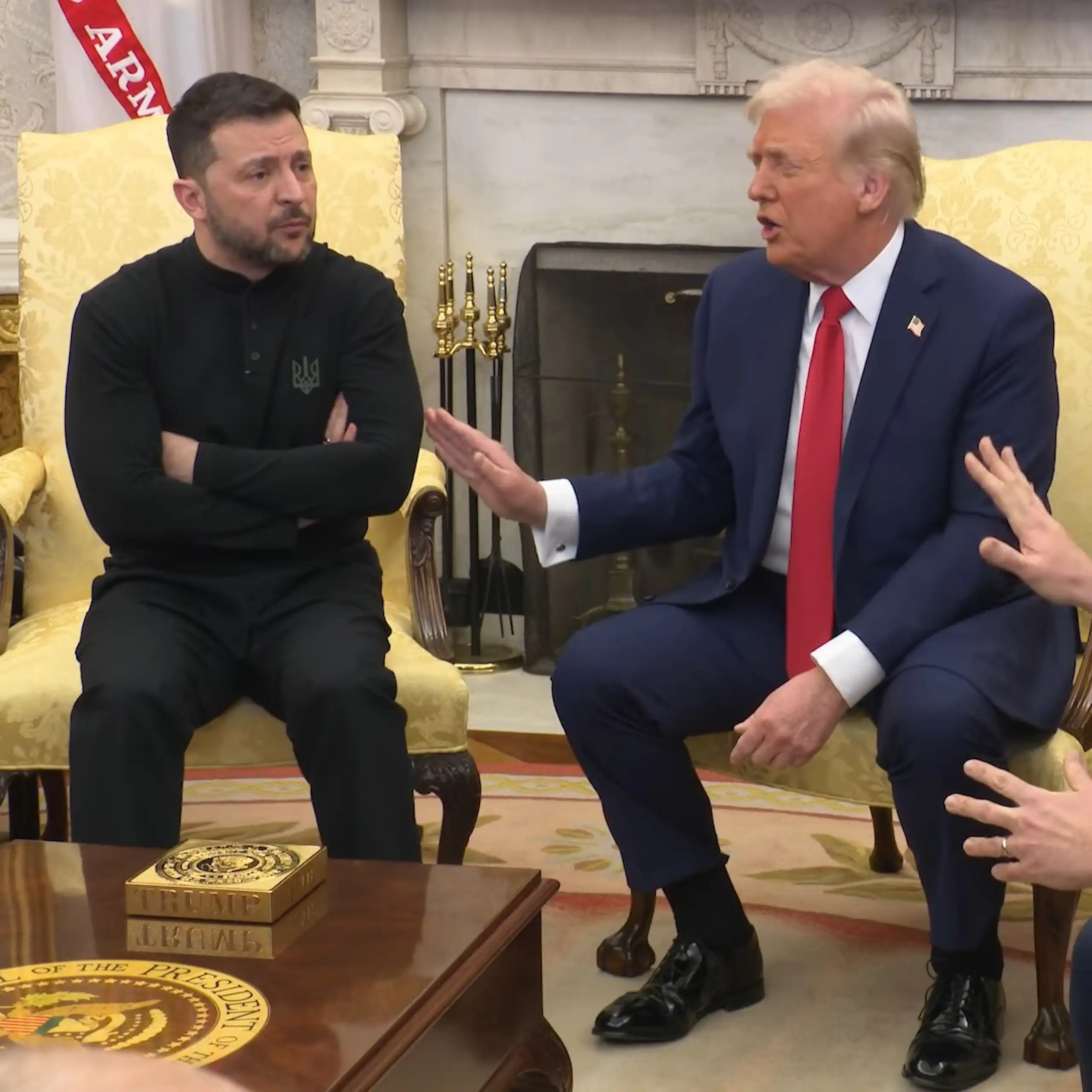 Tres hombres hablan airadamente sentados en una habitación.