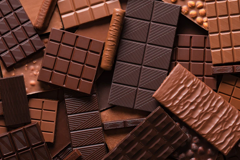 variety of chocolate bars piled on top of each other.