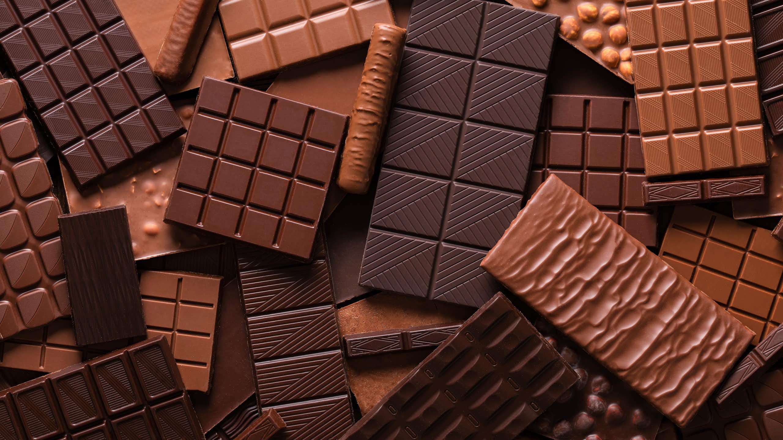 variety of chocolate bars piled on top of each other.