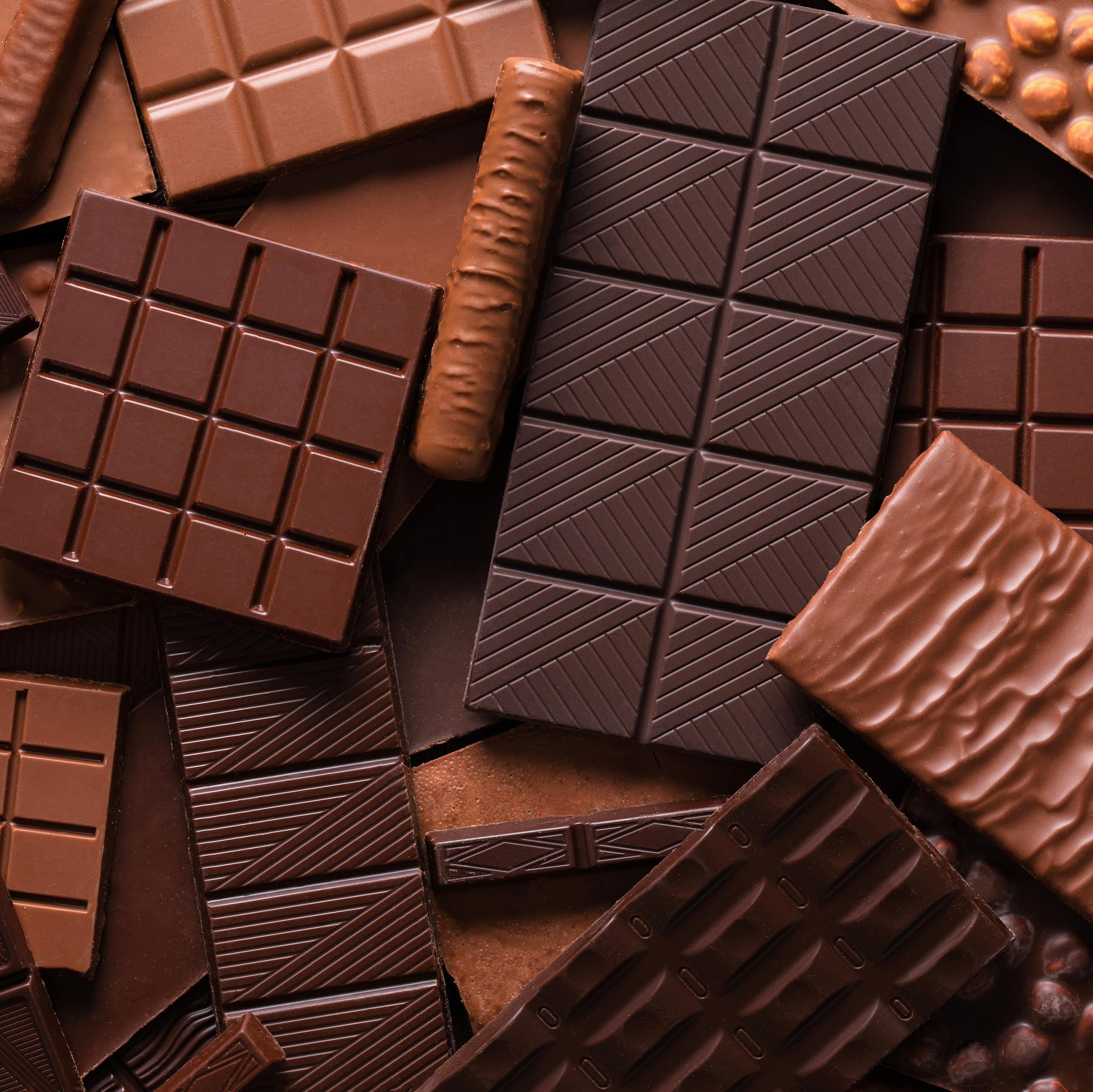 variety of chocolate bars piled on top of each other.