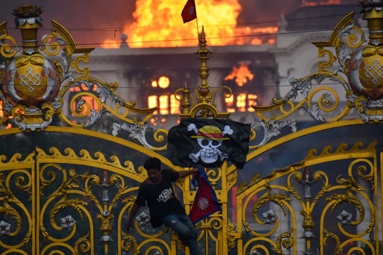 A skull and crossbones flag is seen in front of a blazing building