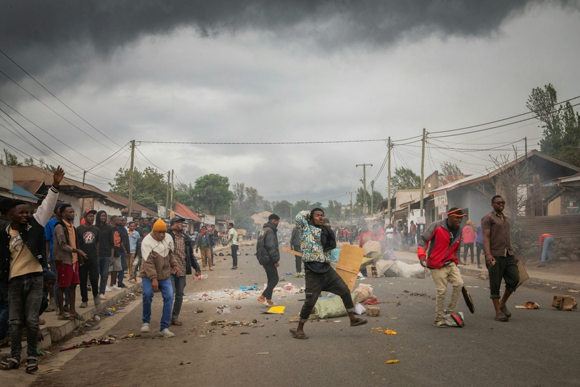People protest in the street as smoke from street fires billow above.