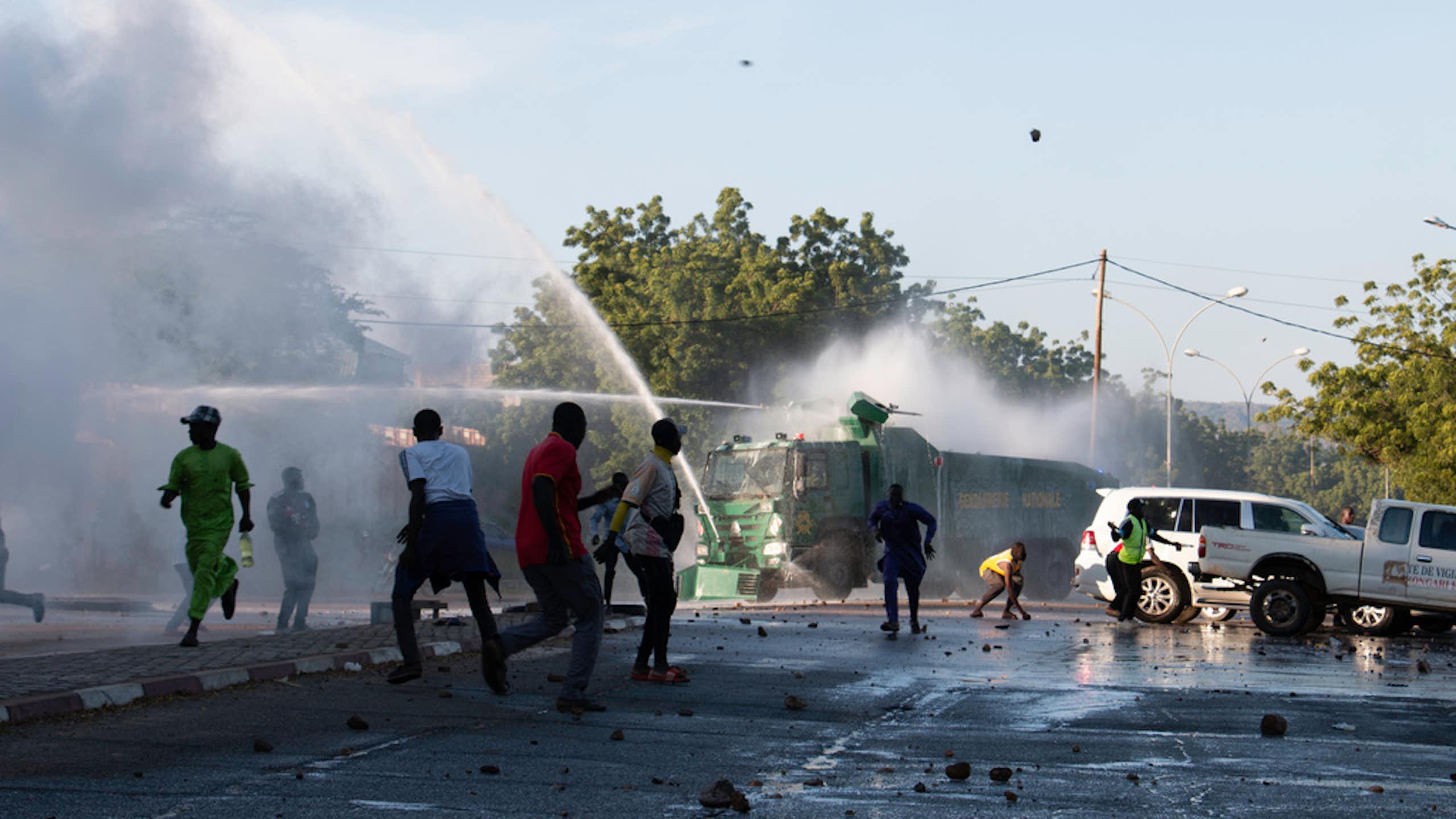 People on the street flee water cannons.