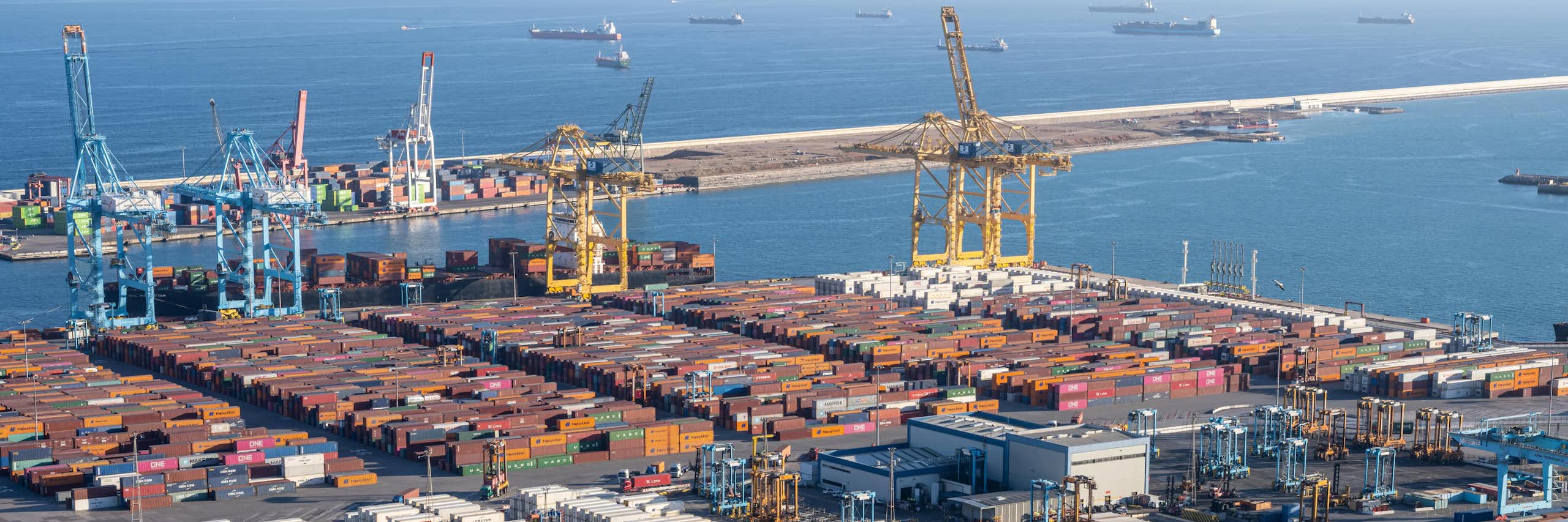 Puerto con contenedores y grúas con barcos de fondo en el mar