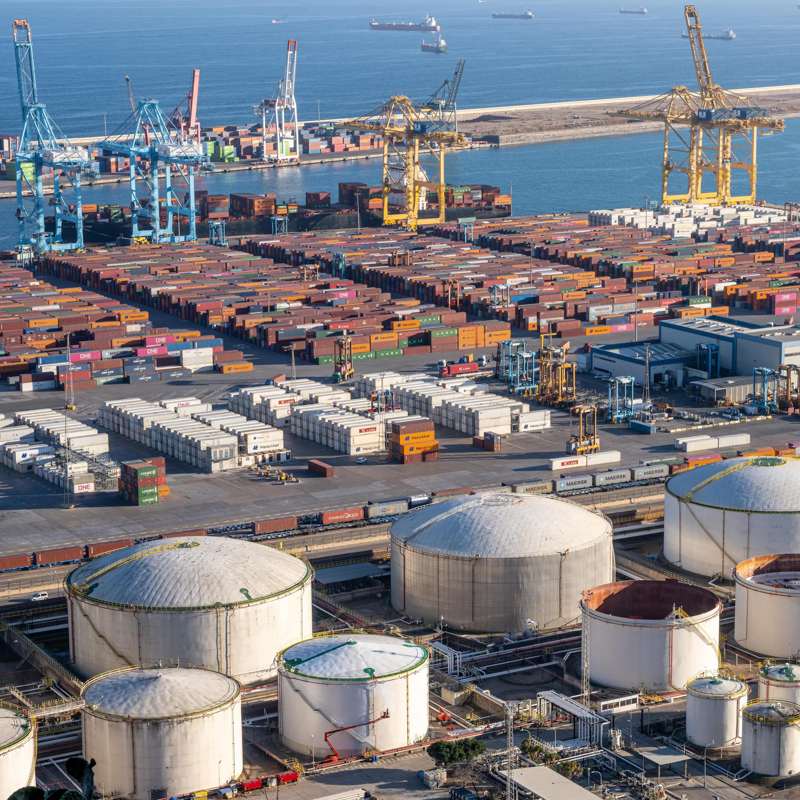 Puerto con contenedores y grúas con barcos de fondo en el mar
