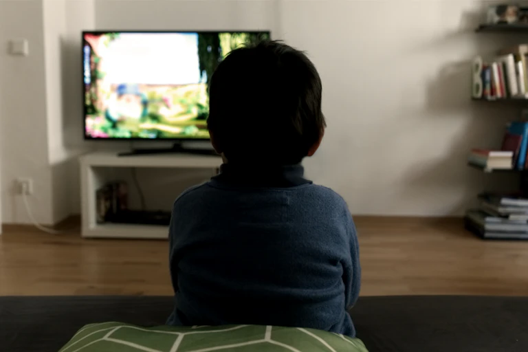 rear view of a young boy watching tv.