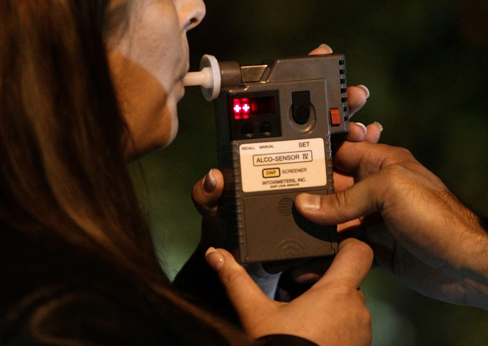 A woman blowing into a handheld breathalyzer 