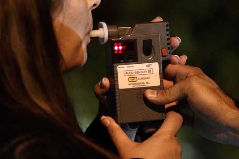 A woman blowing into a handheld breathalyzer