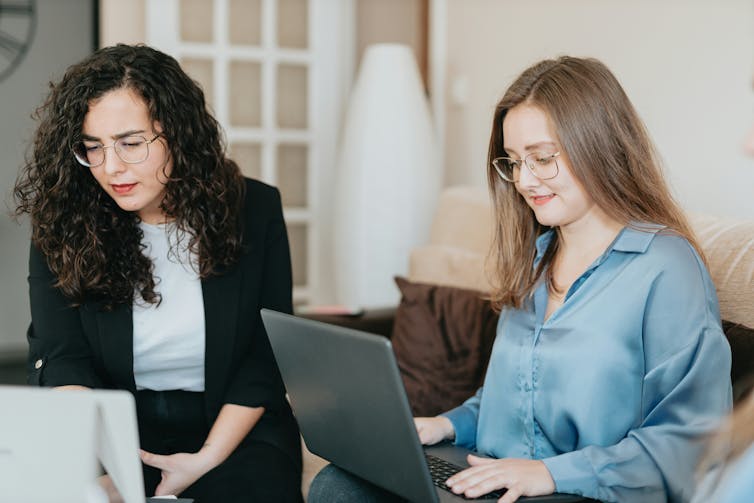 Two women working at laptops in an office