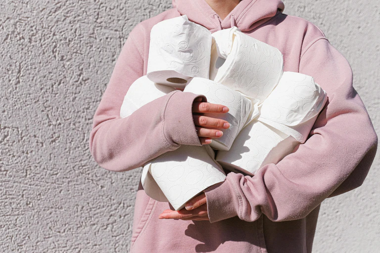 A person holds many rolls of toilet paper.