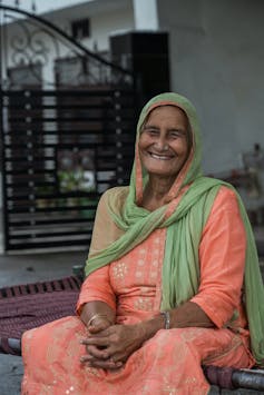 Indian woman in orange dress, sat smiling