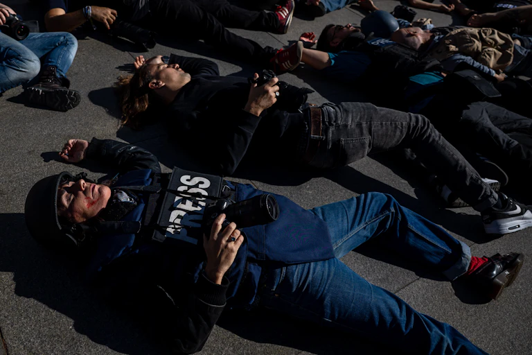 Photographers and journalists in 'press' jackets lying on the ground as if dead
