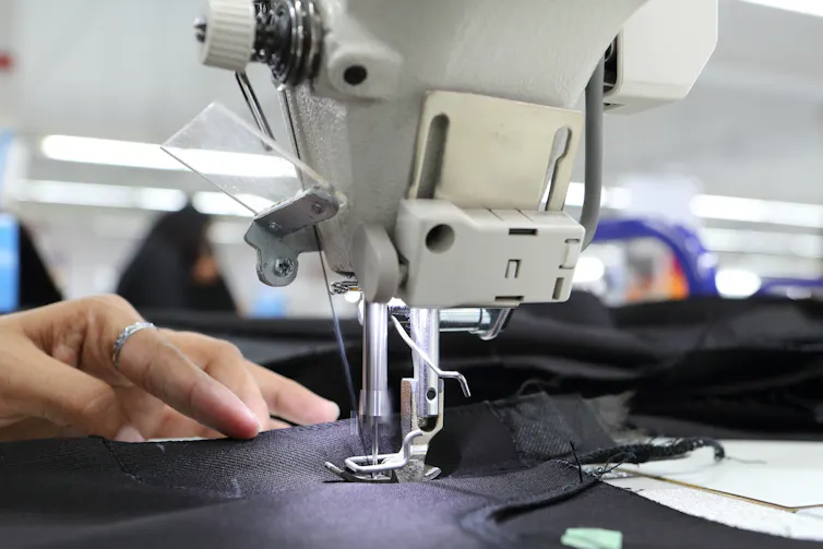 hands of a garment worker at a sewing machine.