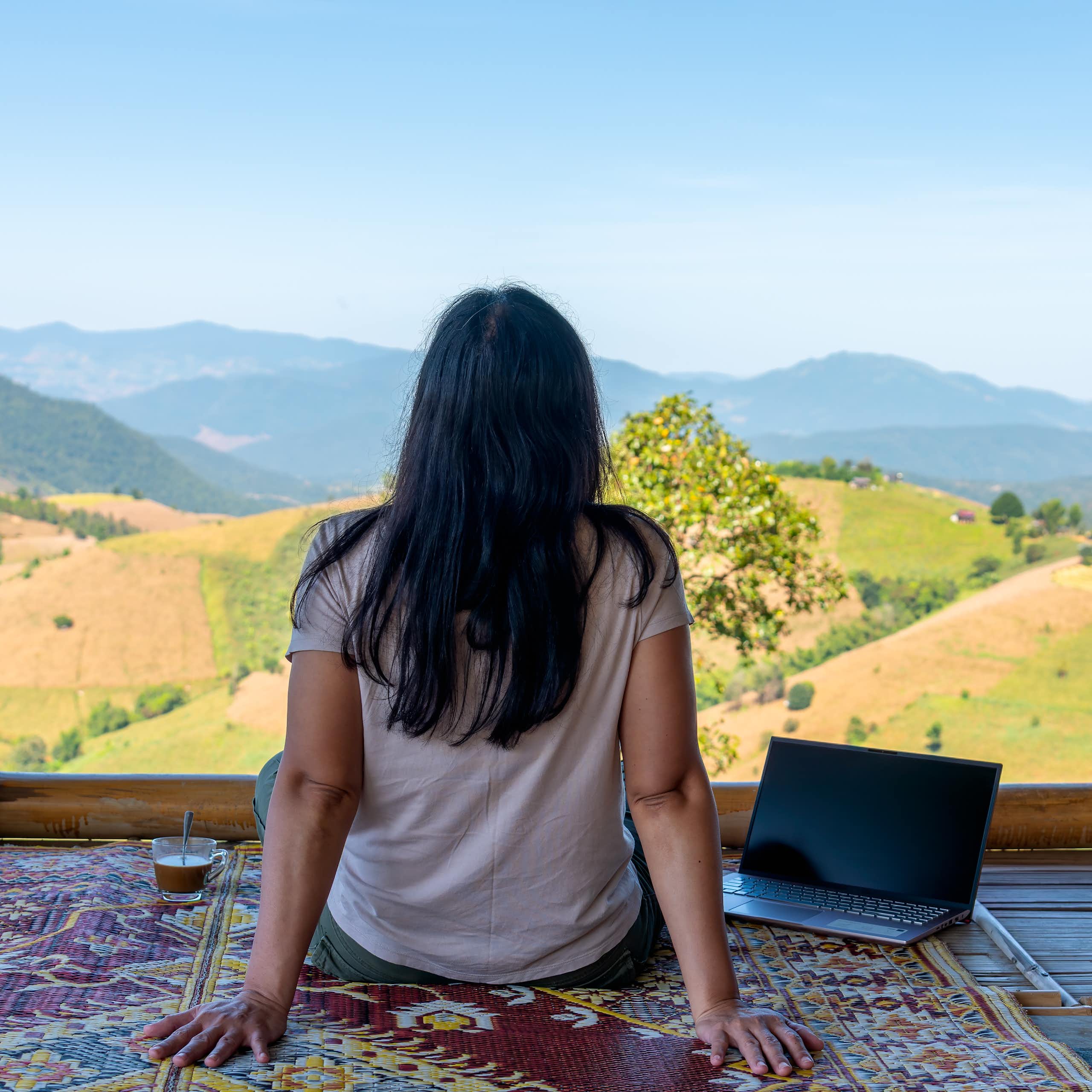 A digital nomad works on their laptop while looking out on terraced rice fields in Chiang Mai, northern Thailand.