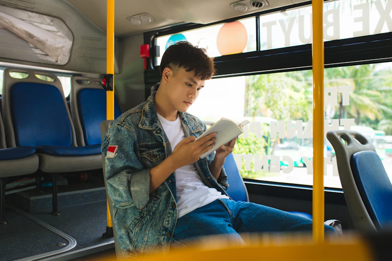 Young man reading on bus
