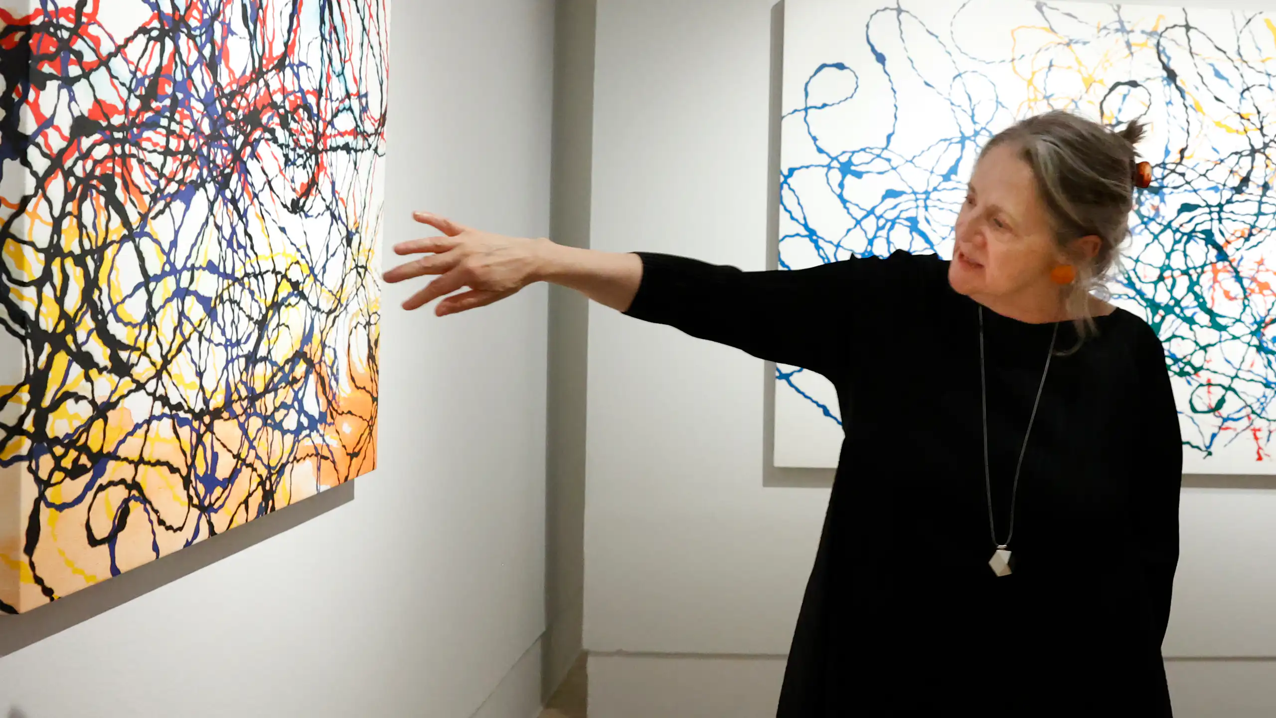 Una mujer señala un cuadro blanco con líneas de colores.