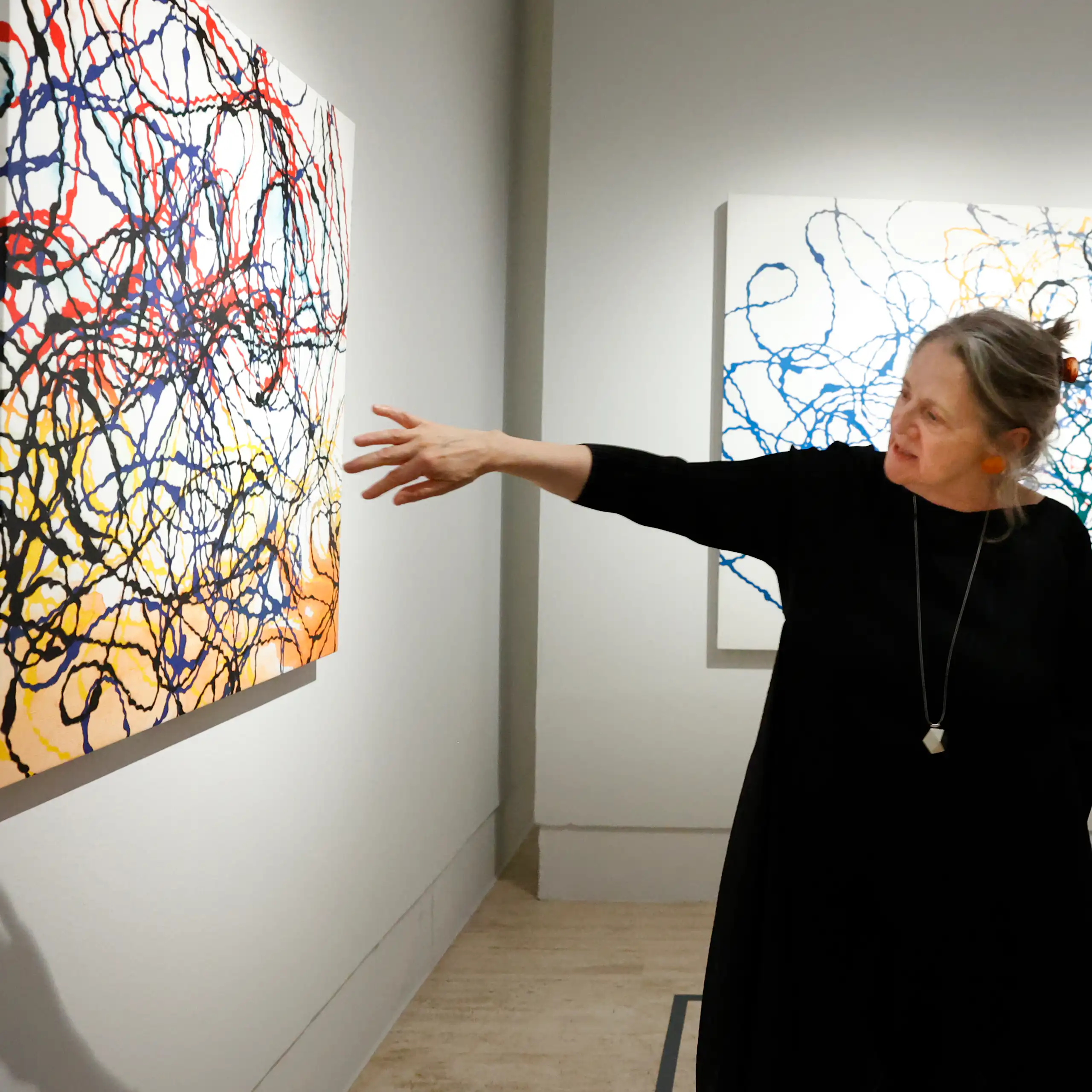 Una mujer señala un cuadro blanco con líneas de colores.