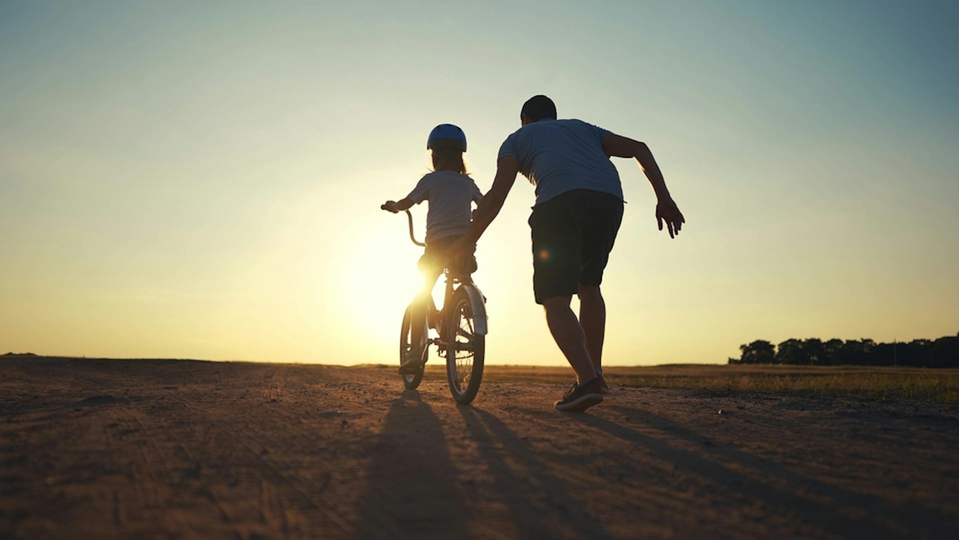 Un père qui aide son fils à faire du vélo