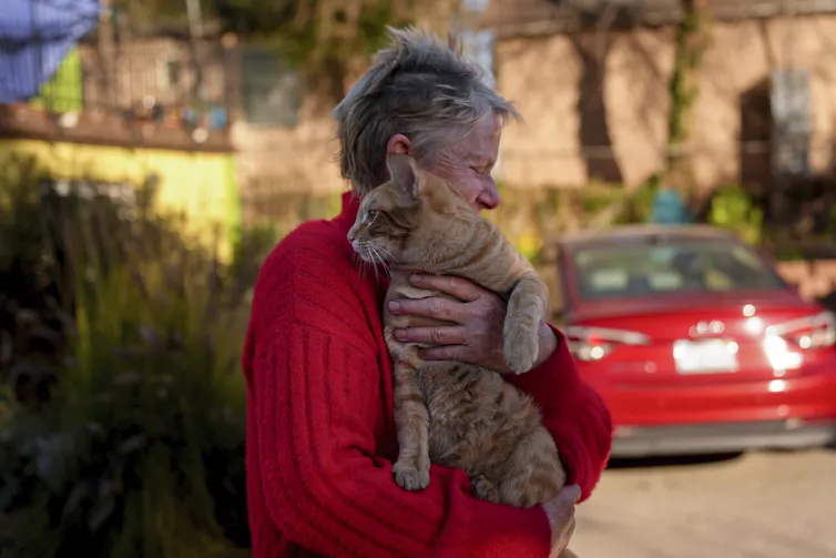 A woman closes her eyes as she hugs her cat.