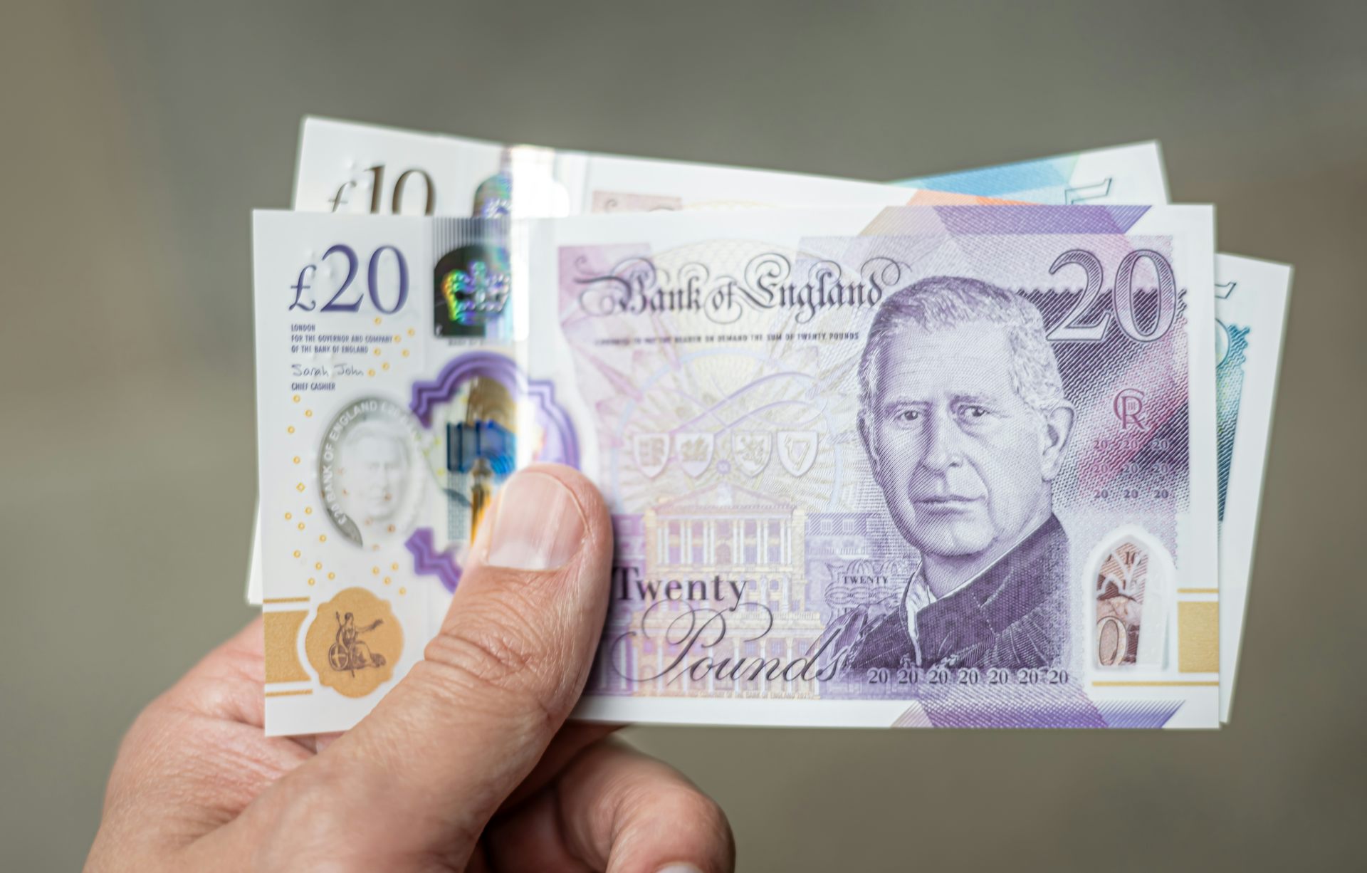 Close up hand holding a stack of 20 pound notes