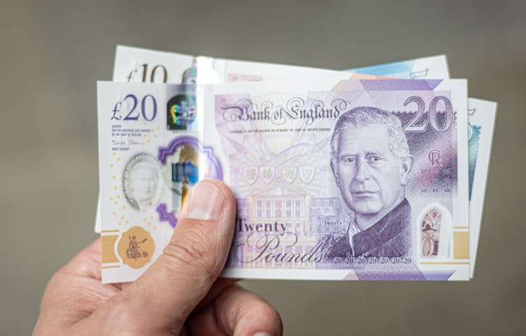 Close up hand holding a stack of 20 pound notes