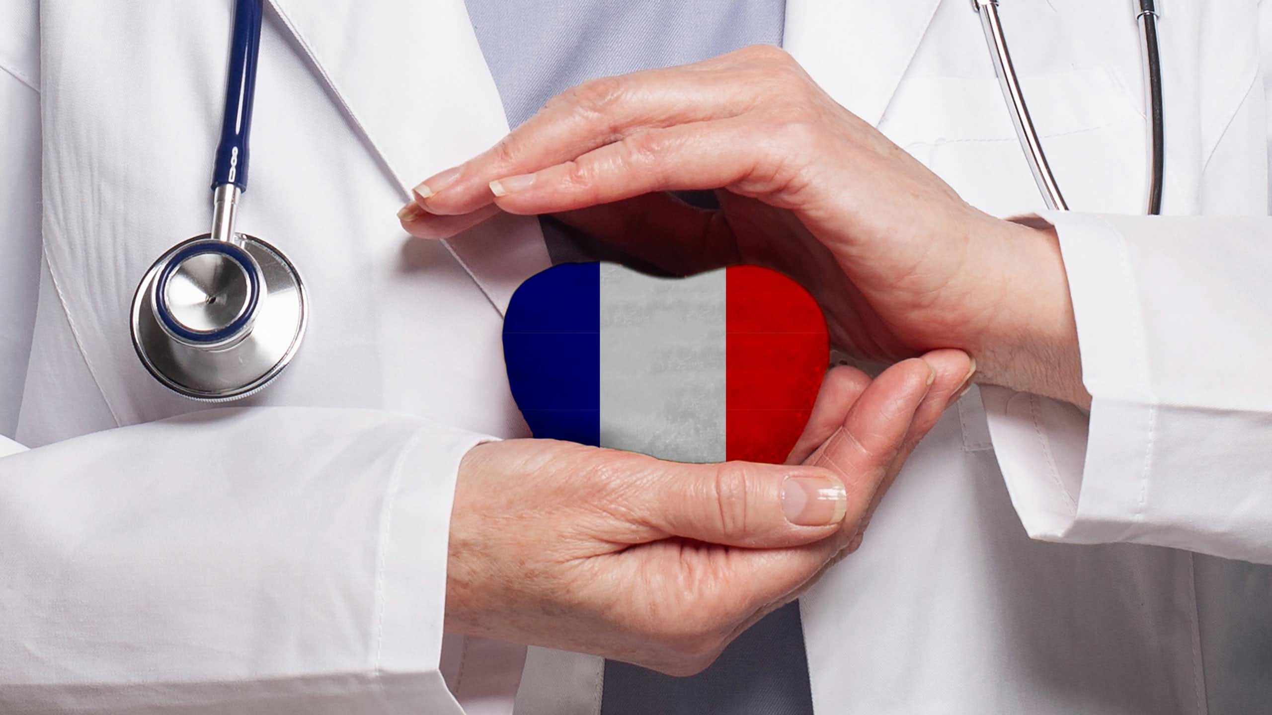 Médecin tenant un coeur avec un drapeau français dans ses deux mains.