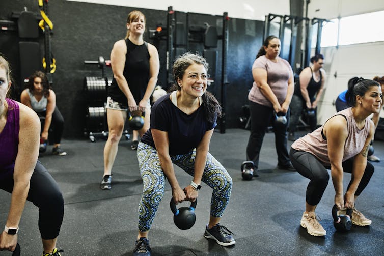 A group of women doing kettlebell swings during class in gym