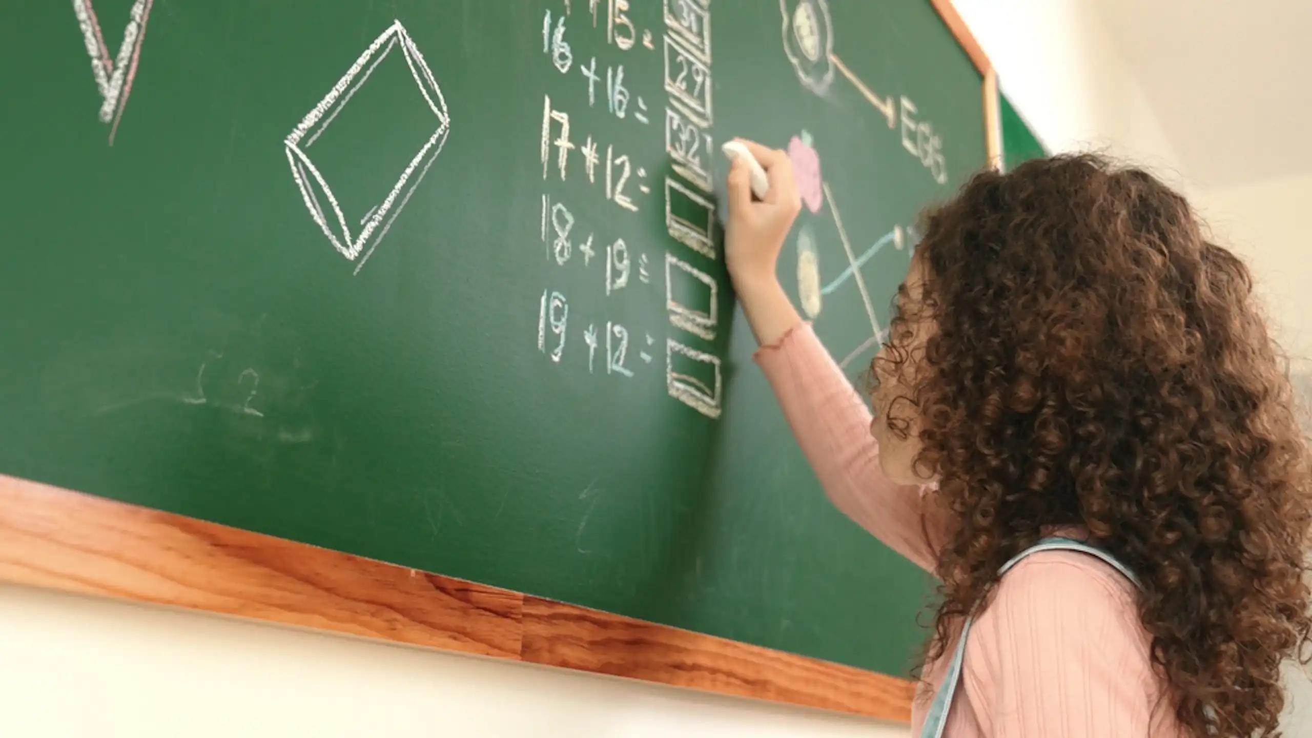 Une élève résout des opérations de maths sur un tableau.