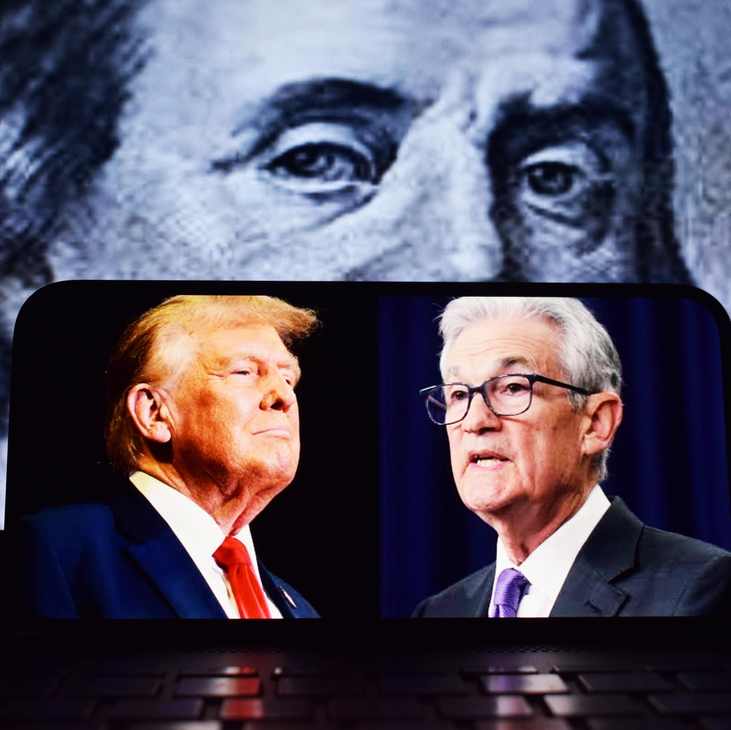 Donald Trump et Jerome Powell sur un portable avec un billet de dollar en fond.
