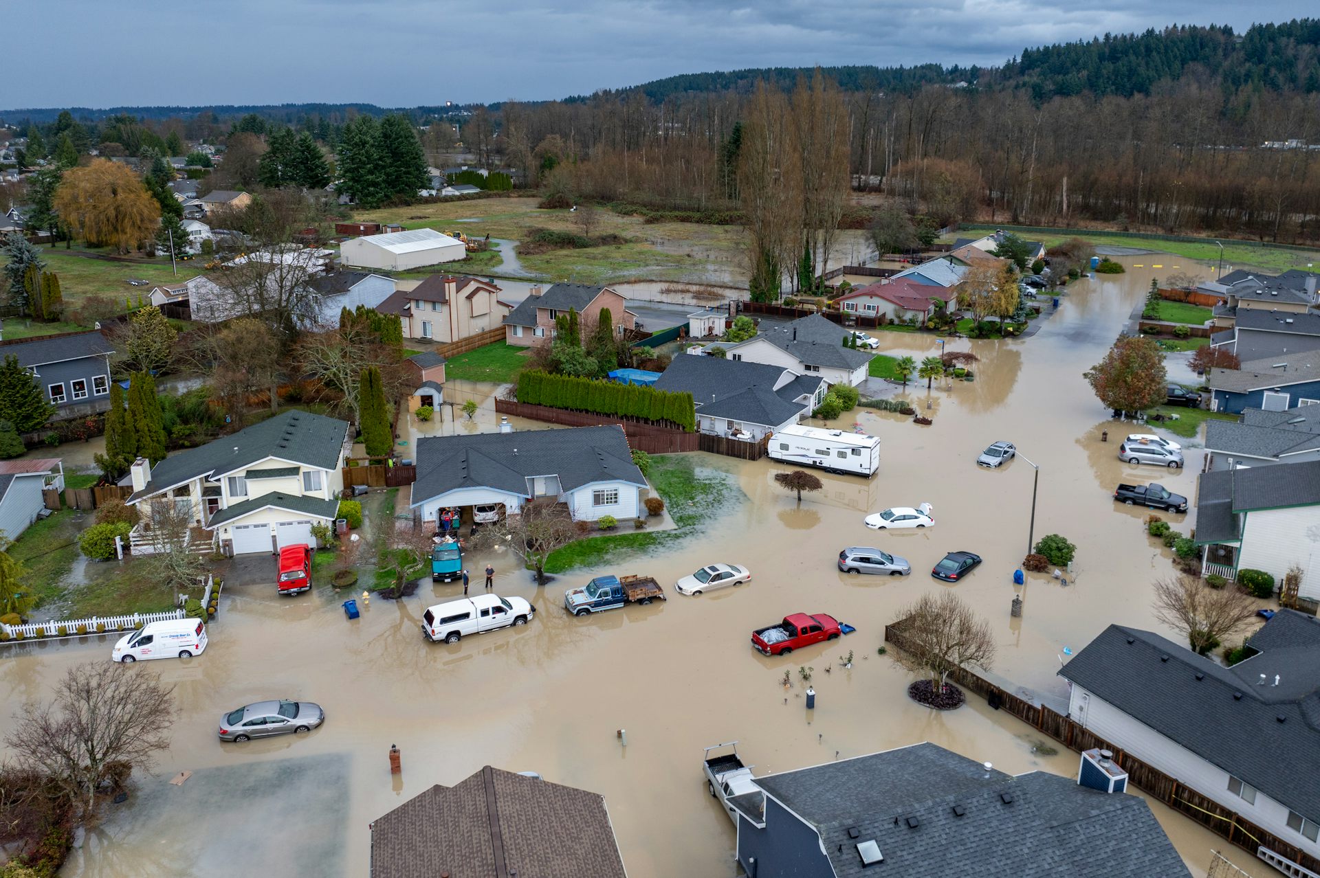 An arial view of a neighborhood inudated with flood water and the river behind where the levee breached.
