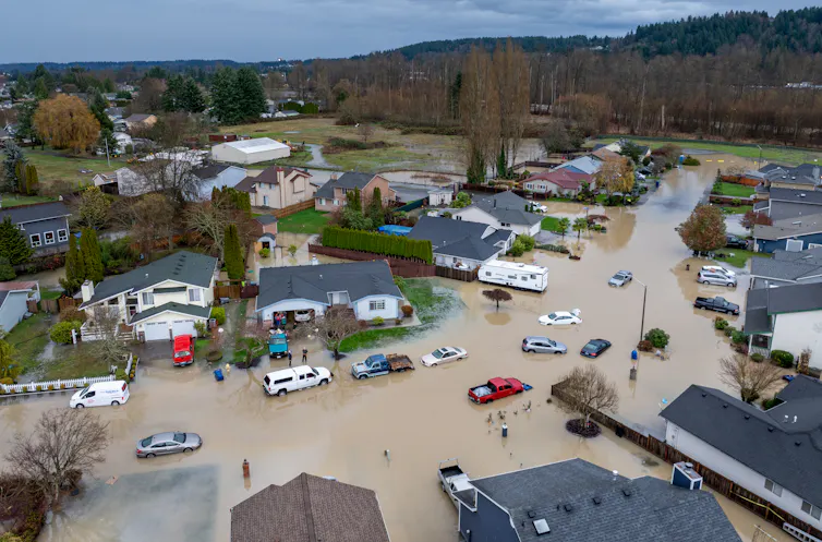 An arial view of a neighborhood inundated with floodwater and the river behind where the levee breached.