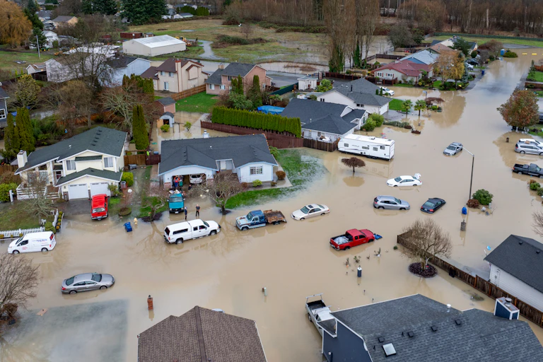 An arial view of a neighborhood inudated with flood water and the river behind where the levee breached.