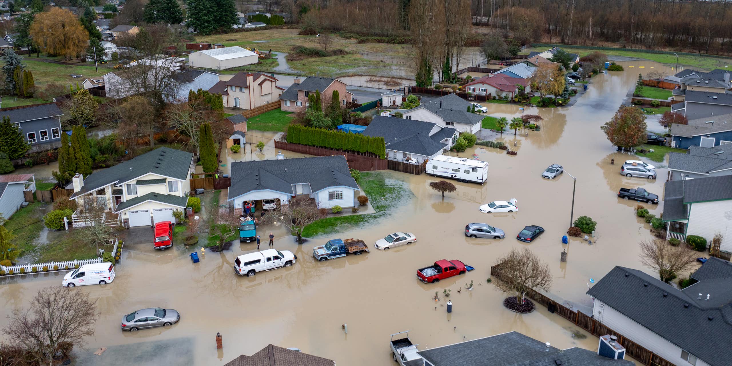An arial view of a neighborhood inudated with flood water and the river behind where the levee breached.