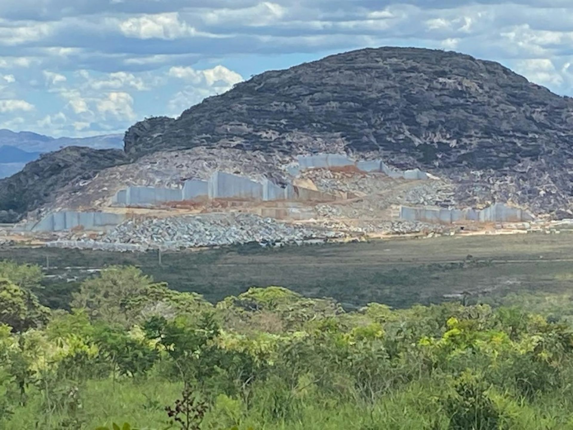 Foto mostra monte com um corte na rocha para exploração do quartzito