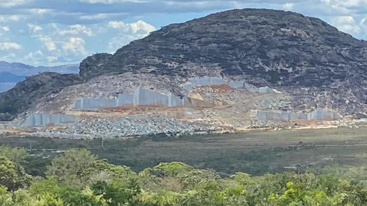 Foto mostra monte com um corte na rocha para exploração do quartzito