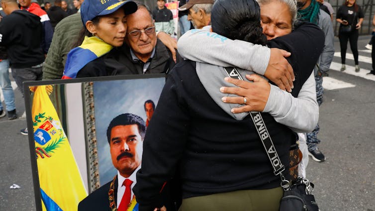 People embrace and hold up a picture of deposed Venezuelan president, Nicolás Maduro.