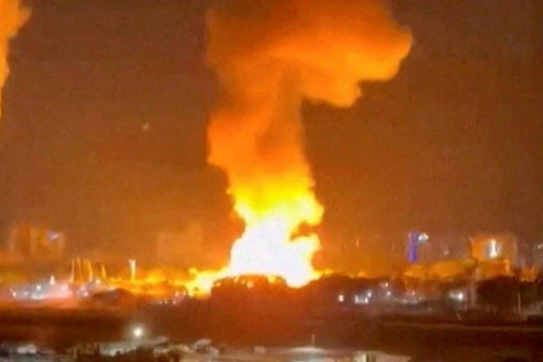 Fotograma nocturno de una ciudad con llamas y humo.