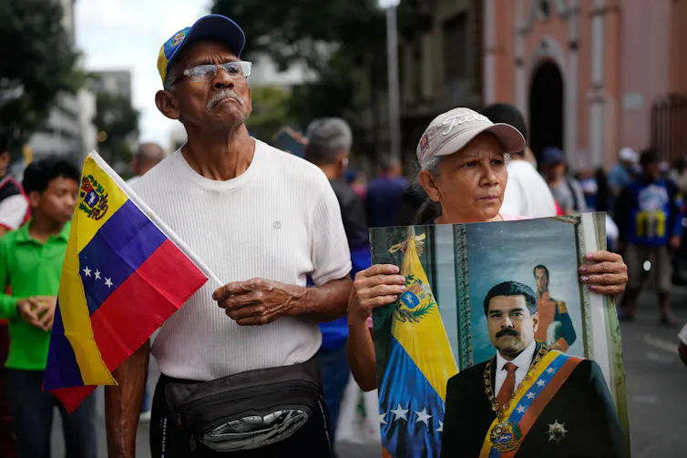 Pessoas seguram bandeiras nacionais e um retrato de um político.