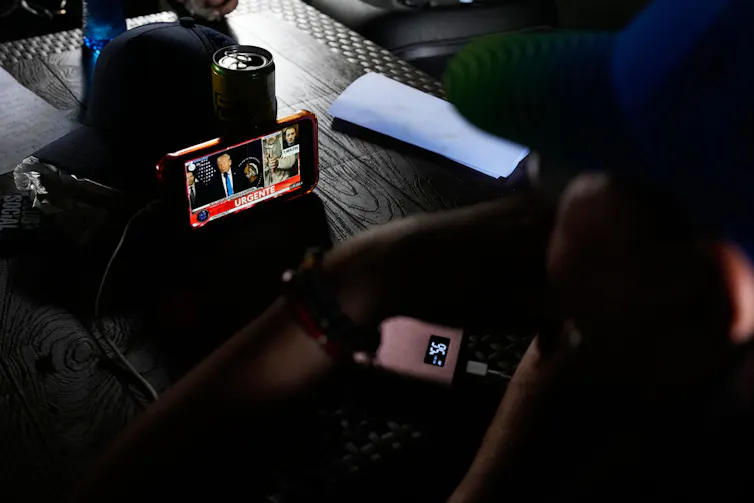 Pessoas assistem a uma coletiva de imprensa transmitida em um smartphone.