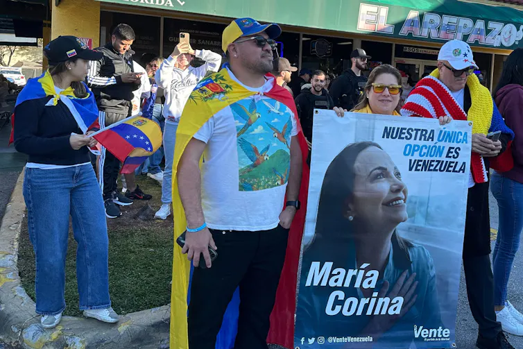 Manifestantes se reúnem, alguns com bandeiras e outros com cartazes políticos.