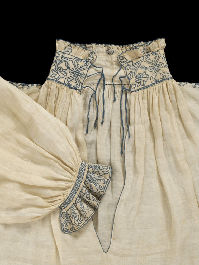 A linen shirt with blue embroidery around the collar and cuffs.